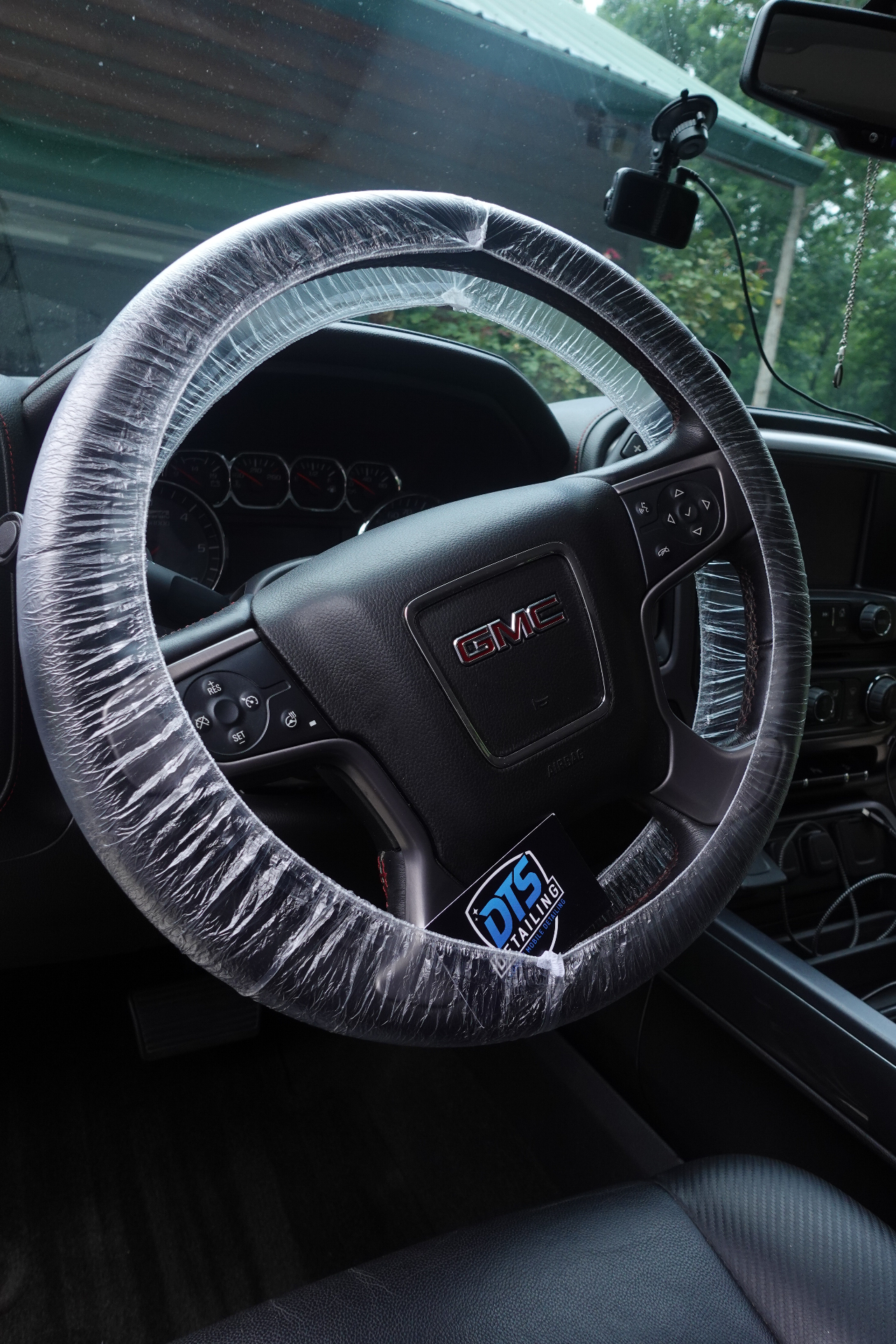 Close-up of DTS Detailing branded steering wheel cover protecting a GMC Sierra during interior detail