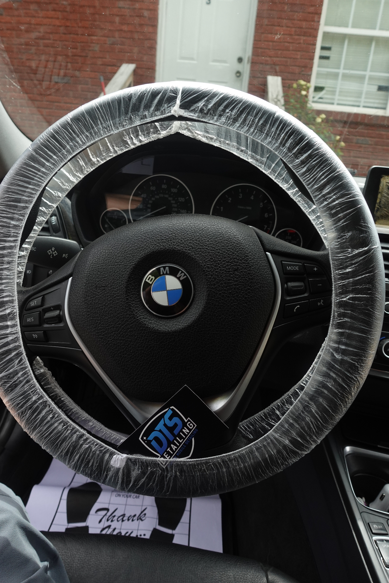 Close-up of DTS Detailing protective steering wheel cover on a BMW during a mobile interior detail