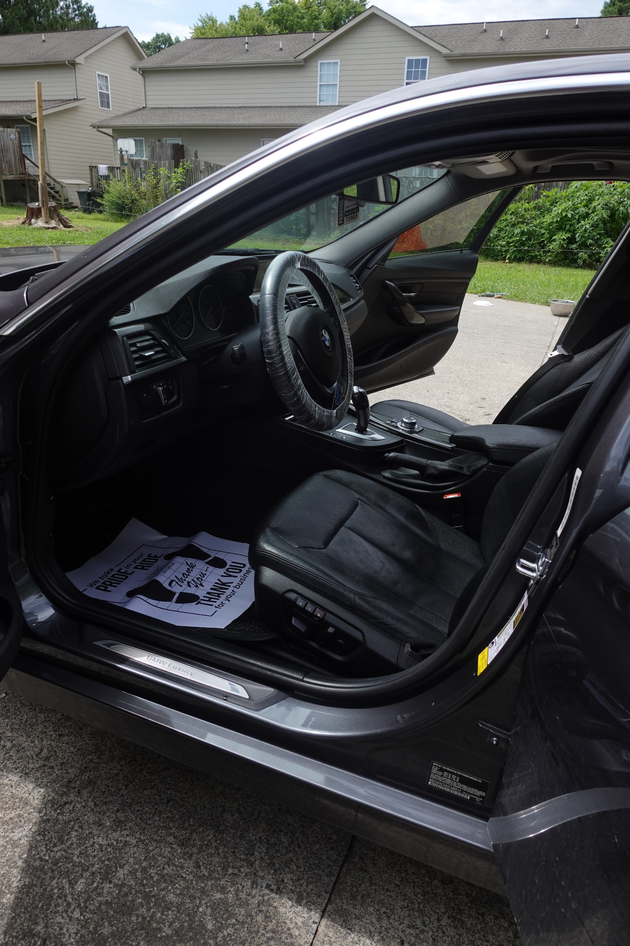 BMW driver door open showing freshly detailed leather seats, polished sill, and clean interior